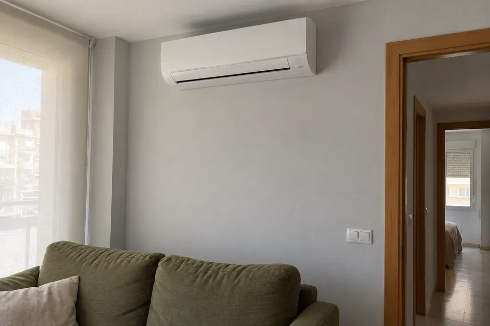 Split de pared en un salón con sofá verde y cortina enrollable