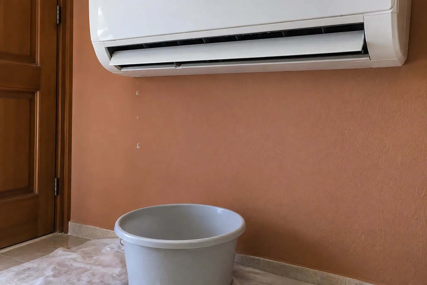 Gotas de agua bajo un split interior y recipiente para proteger el suelo Gotas de agua bajo un split interior y recipiente para proteger el suelo